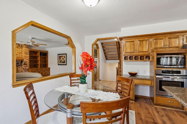 dining area with ceiling fan, dark wood-type flooring, and a textured ceiling