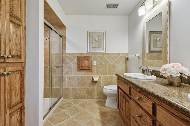 bathroom featuring tile walls, vanity, toilet, and walk in shower