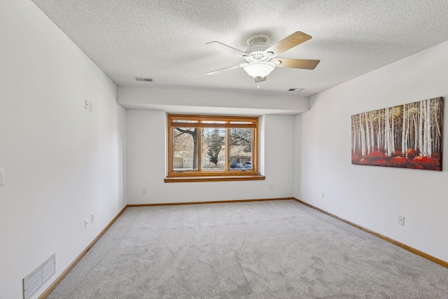 carpeted empty room with ceiling fan and a textured ceiling