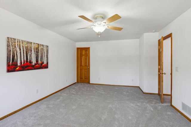 carpeted empty room with ceiling fan and a textured ceiling