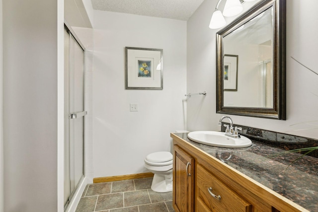 bathroom featuring vanity, a textured ceiling, a shower with shower door, and toilet