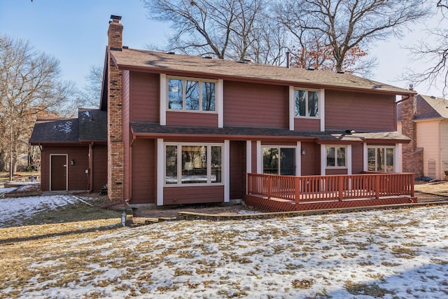 snow covered back of property with a wooden deck