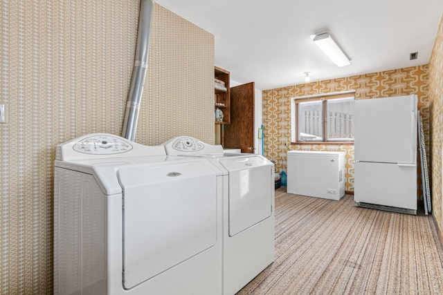 clothes washing area with washer and dryer, visible vents, and wallpapered walls