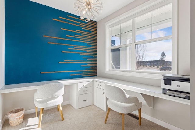 carpeted office space featuring a chandelier and built in desk