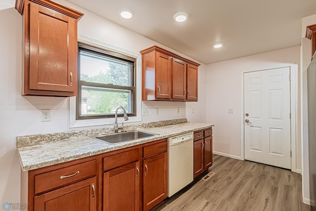 kitchen with white dishwasher, sink, light stone counters, and light hardwood / wood-style flooring