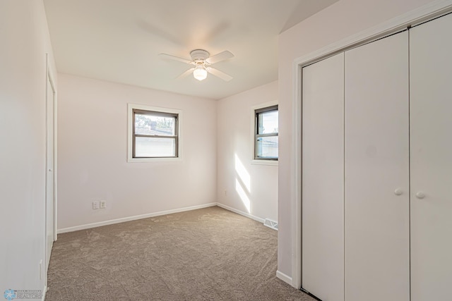 unfurnished bedroom featuring light carpet, a closet, and ceiling fan