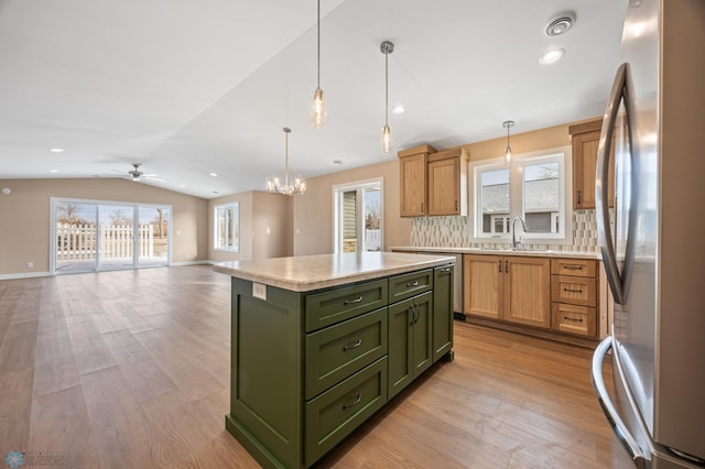 2336 30th Ave S, Fargo, ND 58104 - kitchen featuring vaulted ceiling, a kitchen island, stainless steel refrigerator, decorative light fixtures, and light wood-type flooring