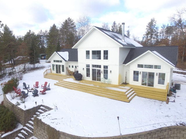 snow covered rear of property featuring central AC unit