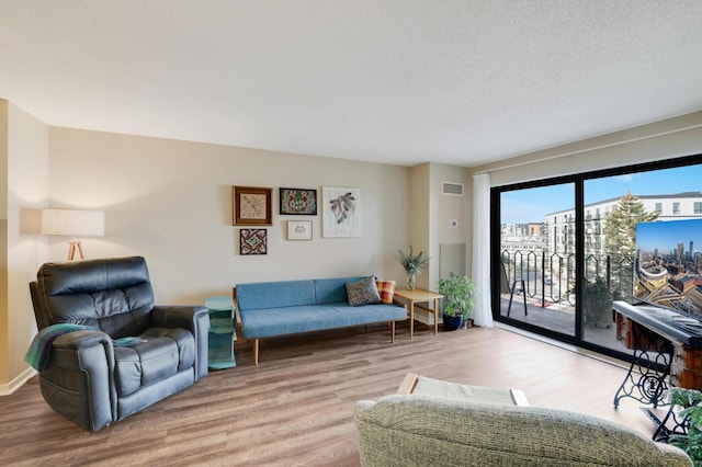 living area with a textured ceiling, visible vents, and wood finished floors