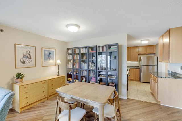 dining room featuring light wood-type flooring and a textured ceiling