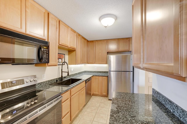 kitchen featuring a textured ceiling, light brown cabinetry, appliances with stainless steel finishes, and a sink