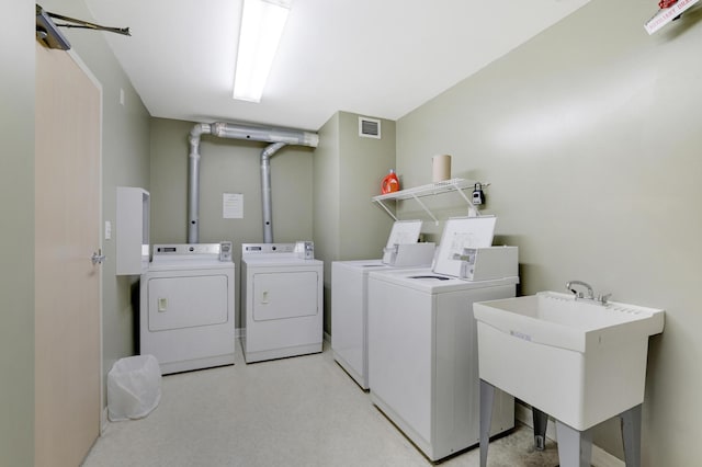 community laundry room featuring a sink, washing machine and clothes dryer, and visible vents