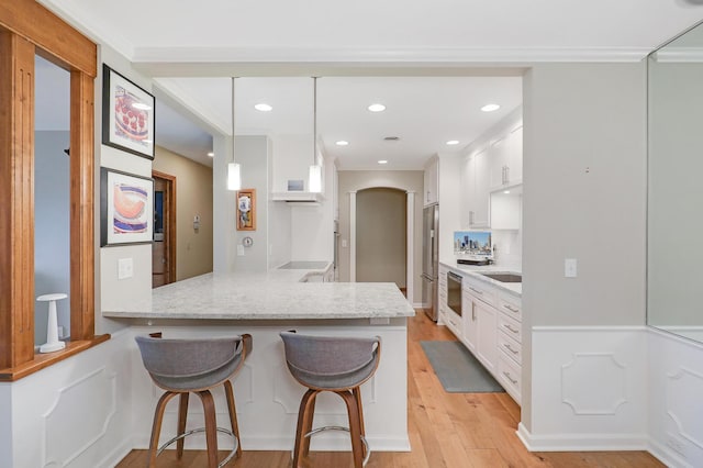 kitchen featuring stainless steel fridge, white cabinetry, hanging light fixtures, a kitchen bar, and kitchen peninsula