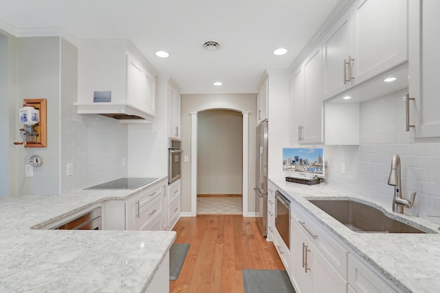 kitchen with white cabinetry, sink, light stone countertops, and appliances with stainless steel finishes