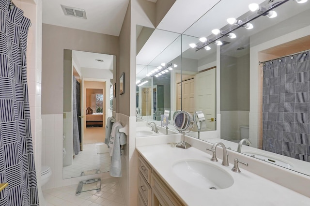 bathroom featuring vanity, toilet, tile patterned flooring, and tile walls