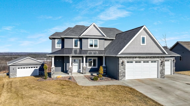 view of front facade featuring a front yard, driveway, a standing seam roof, a porch, and a garage