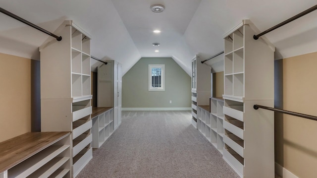 spacious closet with lofted ceiling and light colored carpet