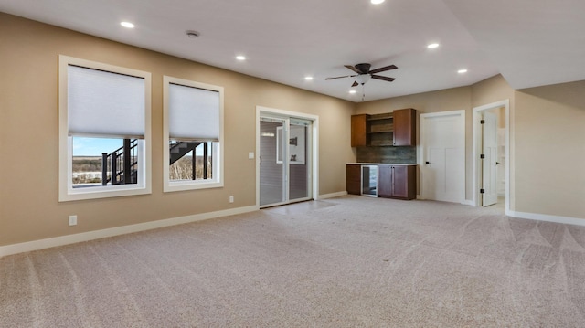 unfurnished living room with light carpet, beverage cooler, and ceiling fan