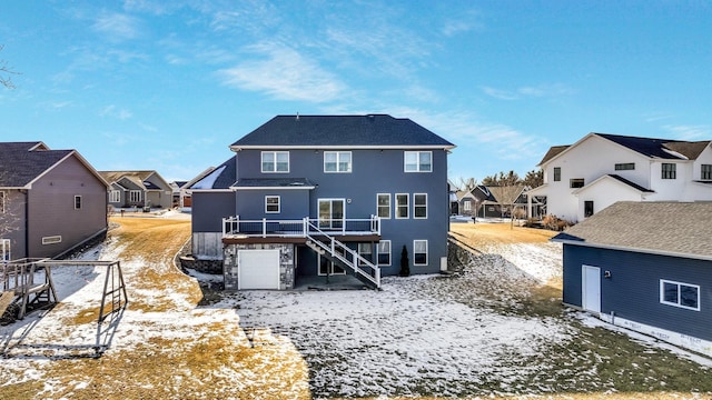 snow covered property with a garage and a deck