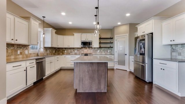 kitchen with hanging light fixtures, a kitchen island, appliances with stainless steel finishes, and white cabinetry