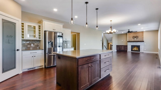 kitchen with white cabinetry, hanging light fixtures, a center island, stainless steel fridge with ice dispenser, and dark wood-type flooring