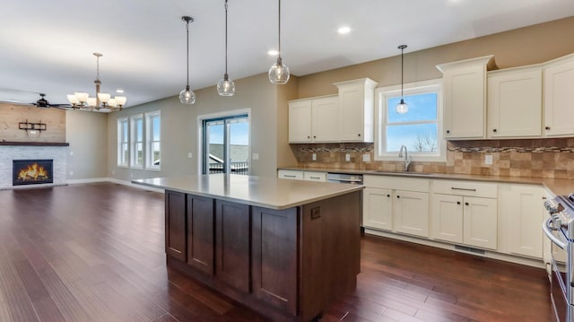 kitchen featuring sink, tasteful backsplash, white cabinets, a kitchen island, and decorative light fixtures