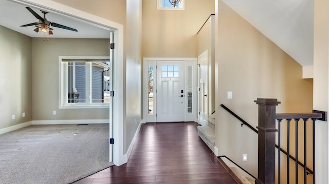 foyer entrance featuring ceiling fan, a healthy amount of sunlight, dark hardwood / wood-style floors, and a high ceiling