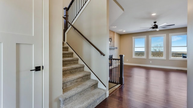 staircase with hardwood / wood-style floors and ceiling fan