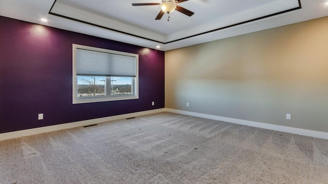 unfurnished room with ceiling fan, a tray ceiling, and carpet