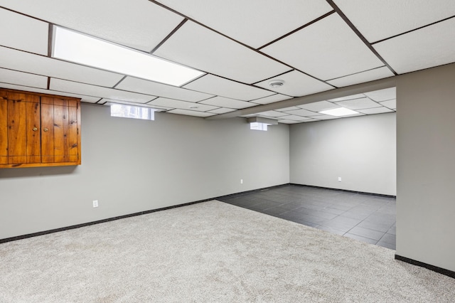 basement with a paneled ceiling and light carpet