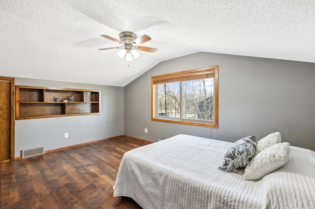 bedroom with vaulted ceiling, ceiling fan, a textured ceiling, and dark hardwood / wood-style flooring