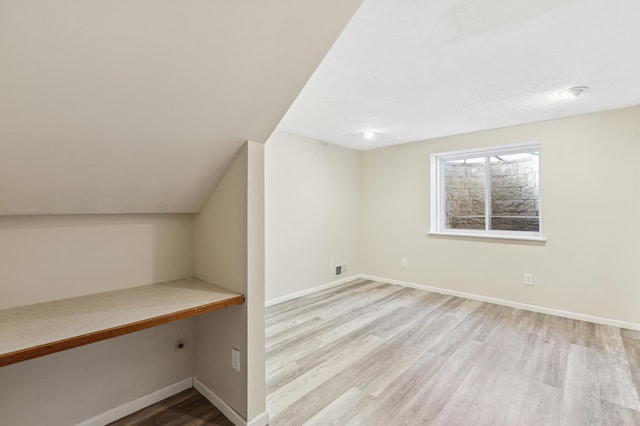 bonus room featuring lofted ceiling, built in desk, and light wood-type flooring