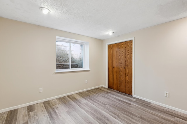 unfurnished room featuring a textured ceiling and light hardwood / wood-style flooring