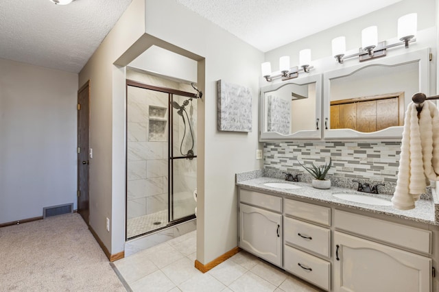 bathroom featuring tasteful backsplash, vanity, a textured ceiling, and a shower with shower door