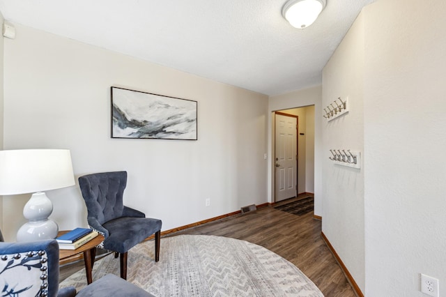 living area with dark wood-type flooring and a textured ceiling