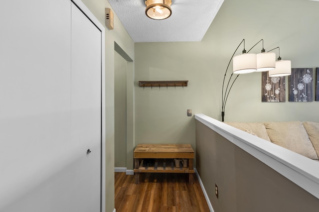 hallway with wood finished floors, baseboards, and a textured ceiling