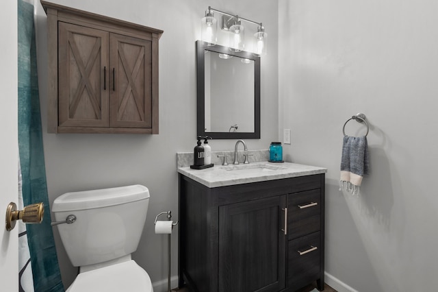 bathroom with vanity, toilet, and baseboards