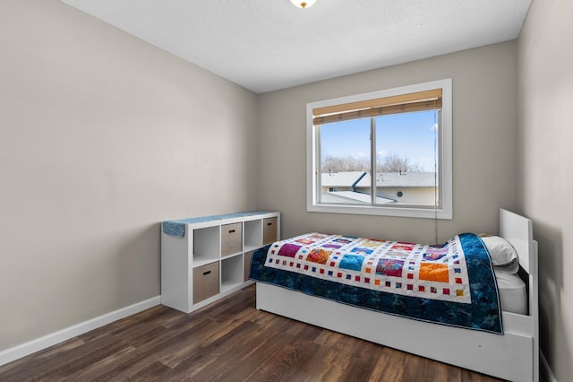 bedroom featuring baseboards, dark wood-style flooring, and a textured ceiling