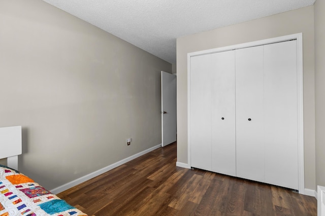 unfurnished bedroom featuring dark wood finished floors, baseboards, a closet, and a textured ceiling