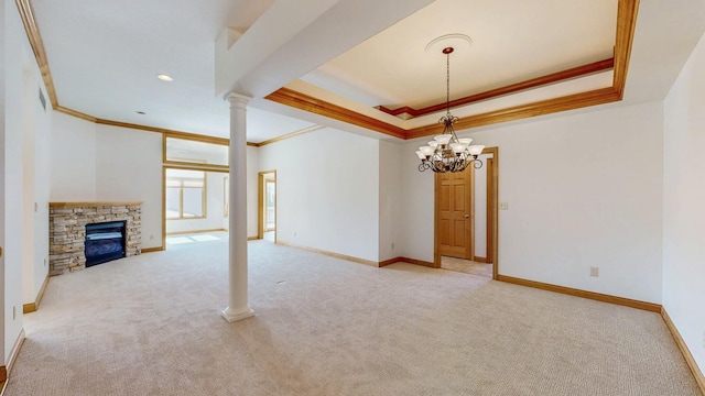 unfurnished living room with baseboards, light colored carpet, a tray ceiling, decorative columns, and a stone fireplace