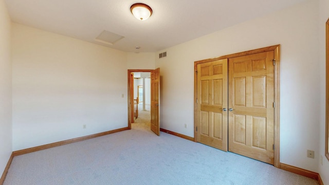 unfurnished bedroom with light carpet, visible vents, a closet, and baseboards