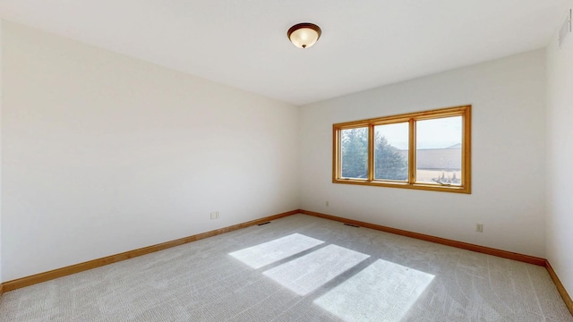 unfurnished room featuring baseboards, light carpet, and visible vents