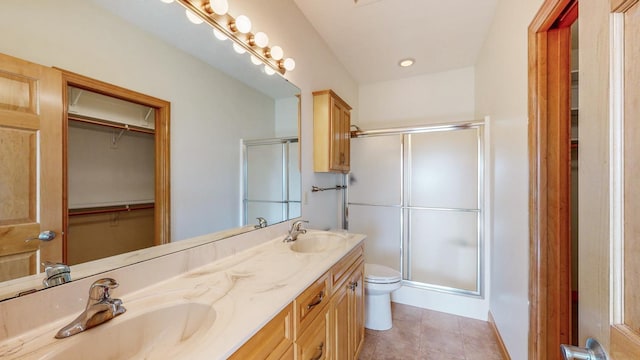 full bath with double vanity, toilet, a stall shower, and a sink