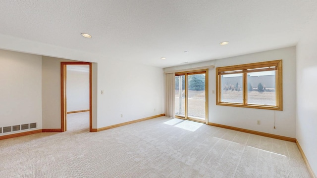 spare room featuring light carpet, visible vents, recessed lighting, and baseboards