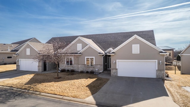 view of front facade with stone siding, driveway, and a shingled roof