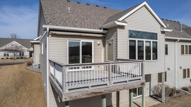 rear view of property with central air condition unit and roof with shingles