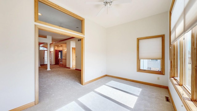 unfurnished room featuring ceiling fan, light colored carpet, cooling unit, baseboards, and visible vents
