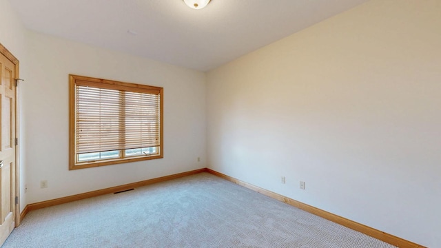 empty room with visible vents, baseboards, and light carpet