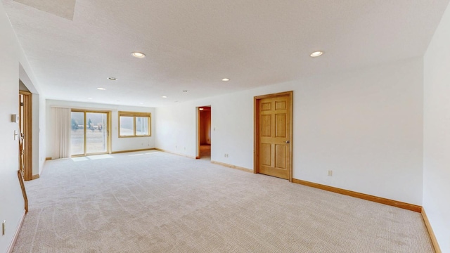 spare room featuring recessed lighting, baseboards, and light colored carpet