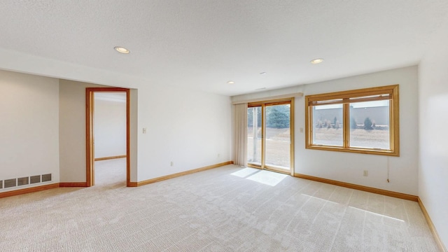 spare room with baseboards, visible vents, and light carpet